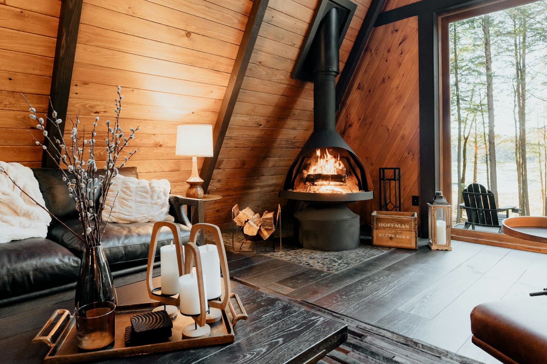 A wood-beamed living room with a lit fireplace