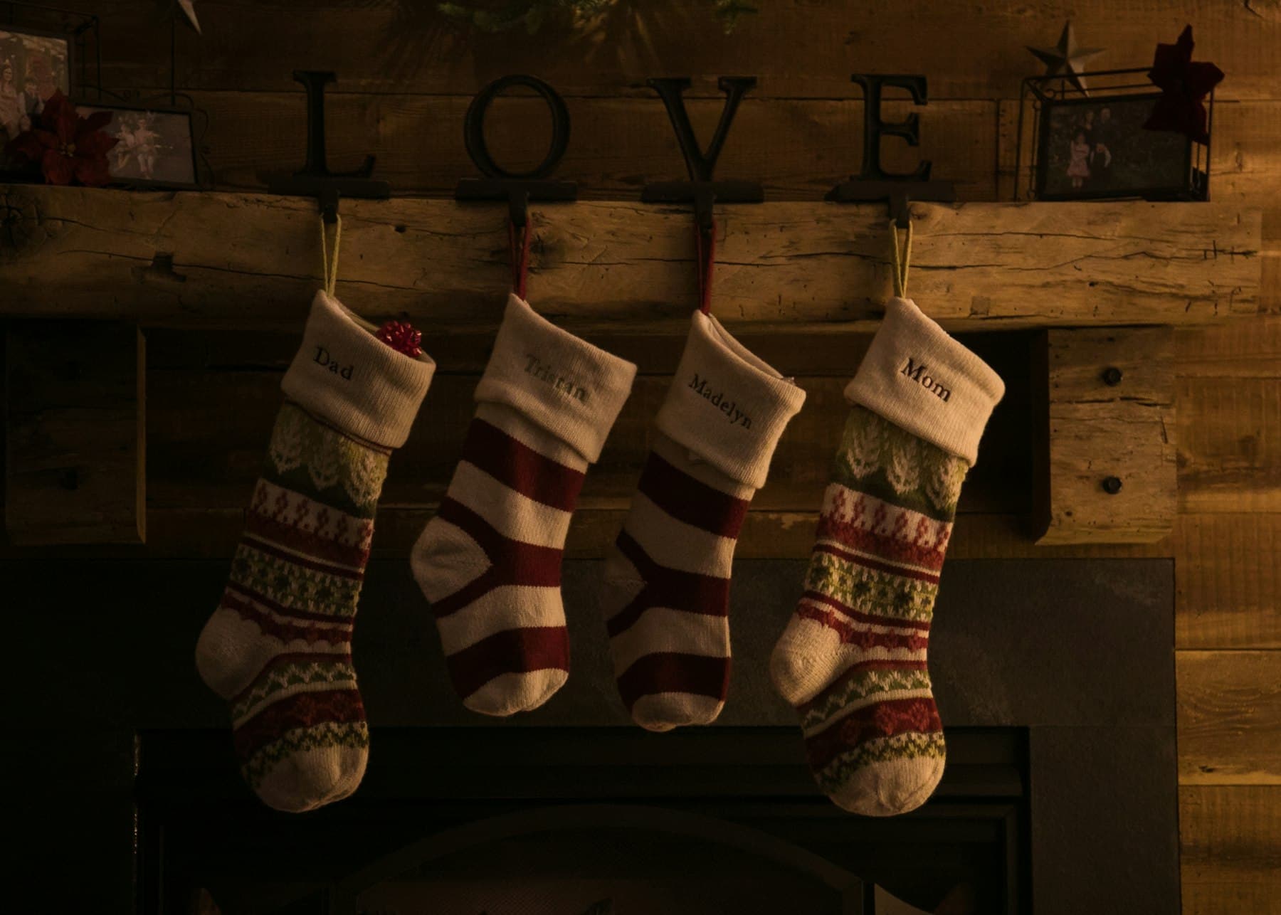 Four knit Christmas stockings hanging from a wooden mantel